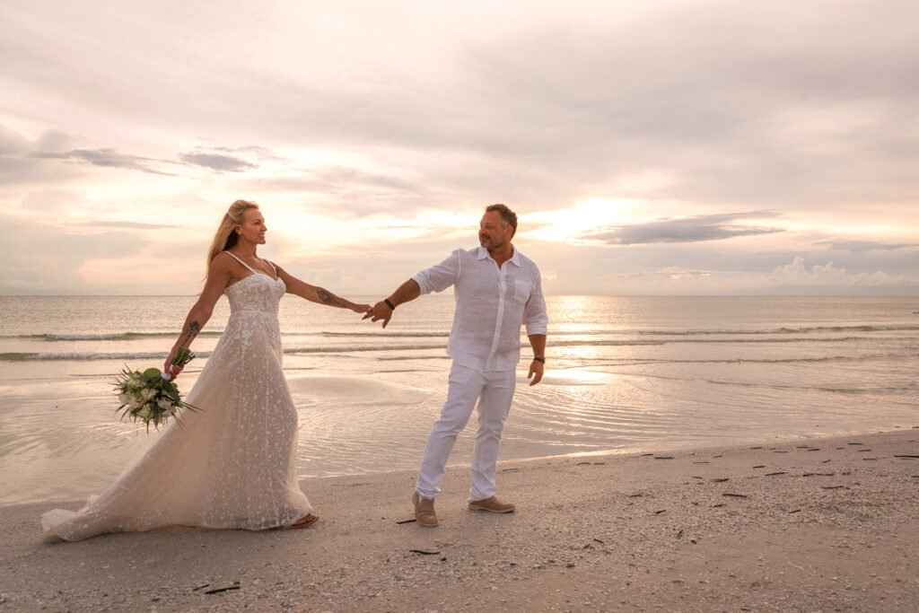 elopement couple walk on beach at sunset